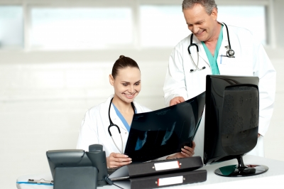 Female and Male doctor analysing xray in front of computer and desk