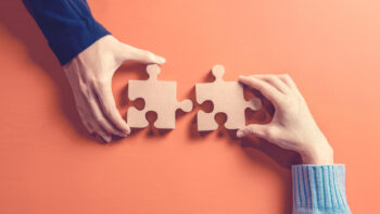 Two hands holding jigsaw, Concept for teamwork Building a success.