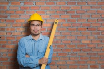 Manufacturing man in shirt against wall with yellow hat and ruler